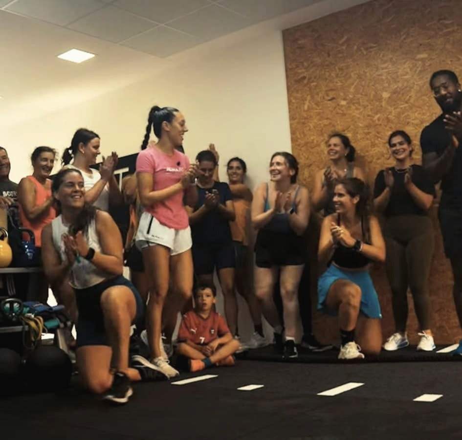 Grupo de alunos e treinadores a aplaudir no estúdio no fim de uma aula.